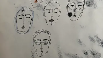 Abstract sketches of five faces on paper.