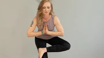 Frau führt Yoga-Positur in ruhigem, grauem Raum aus.