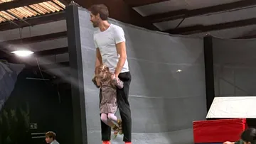 A man lifts a girl in a trampoline park.