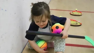 A girl is playing with colorful balls in a gym.