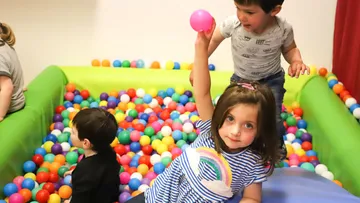 Children play with colorful balls in a ball pit.