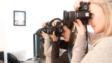 Drei Fotografen machen Fotos in einem hellen Raum.
