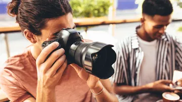 Fotograf hält Kamera, konzentriert auf Aufnahme in Café.