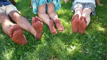Barfüßige Menschen sitzen auf grünem Gras und genießen Sonne.