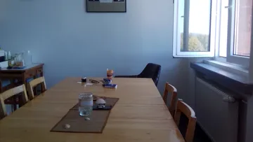 Wooden table with glass water, chairs and window in the background.