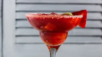 A red cocktail in a sugar-ribbed glass.