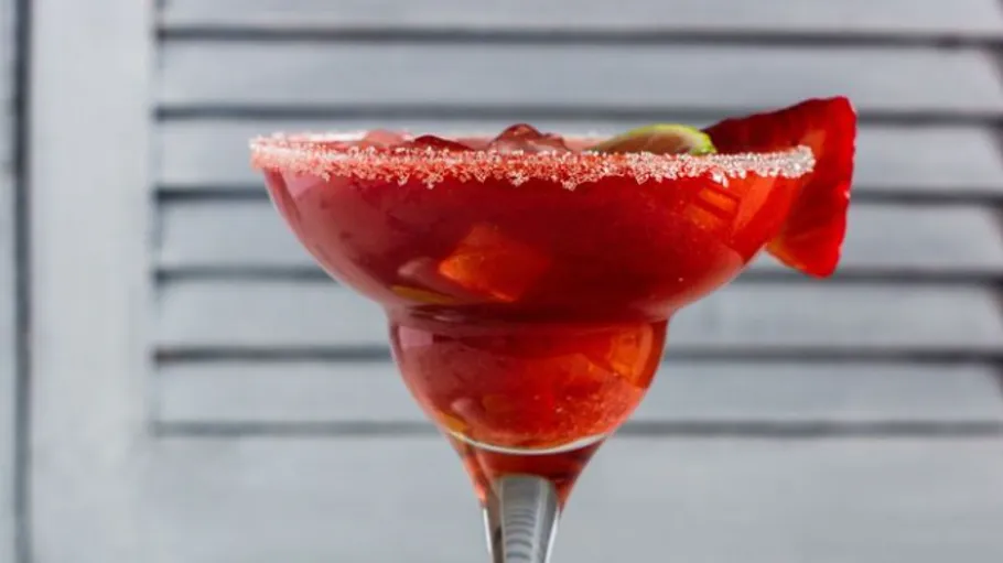 A red cocktail in a sugar-ribbed glass.