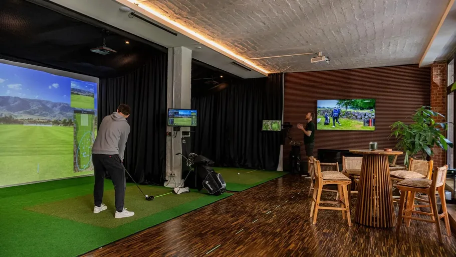 Golfspieler schlägt ab, simulierte Umgebung in modernem Raum.