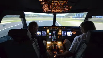 Zwei Personen im Cockpit steuern ein Flugzeug während des Flugs.