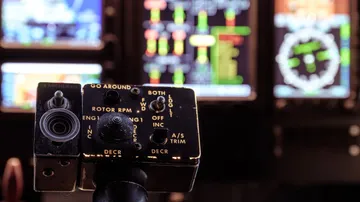 Bedienelement steuert Funktionen in Cockpit mit Displays im Hintergrund.