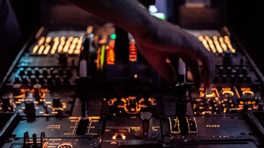 Hand turn the controller on an illuminated control panel in the dark.
