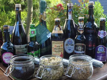 Flaschen mit Bier und Zutaten stehen auf einem Tisch.