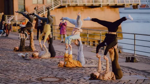 People do acrobatic exercises on a waterside jetty.