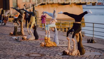 Sechs Personen machen Yoga-Übungen am Flussufer.