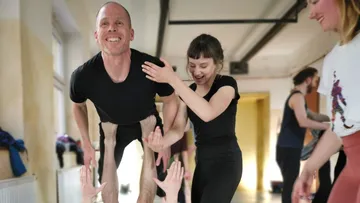 Human acrobatics: People support others in a room.
