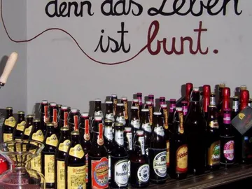 Bierflaschen stehen auf einem Tisch, eine Wand hat Schrift.