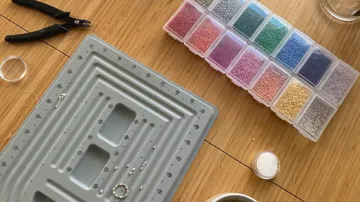 Perlen und Werkzeuge zum Schmuckmachen auf einem Tisch.
