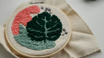 Embroidery frame with green plant and red background