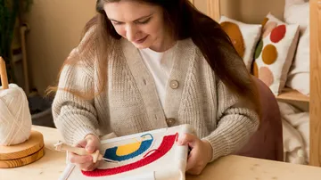 Woman embroidering colorful fabric in bright surroundings.