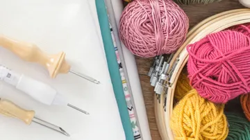 Balls of wool and tools lie on a wooden table.