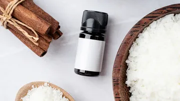 Essential oil lies next to cinnamon sticks and salt peel.
