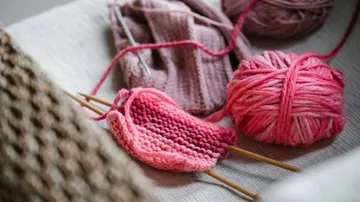 Balls of wool and knitting needles lie on a table.