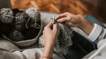A person knits in a cozy room.