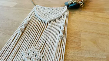 Macrame wall hanger with dried flowers on a wooden table.