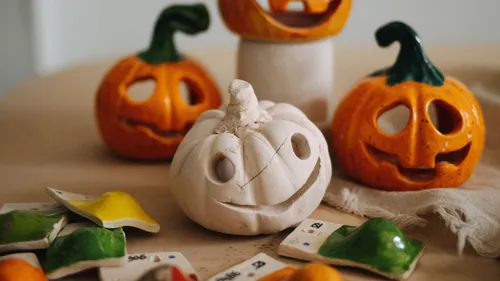 White pumpkin figure smiles, surrounded by pumpkins and colors.