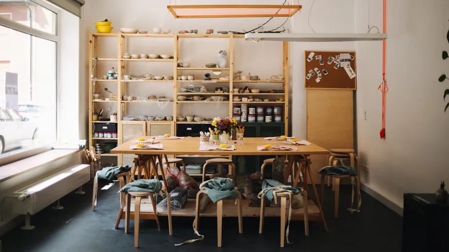 Holztisch in kreativem Raum mit Stühlen und Materialien.