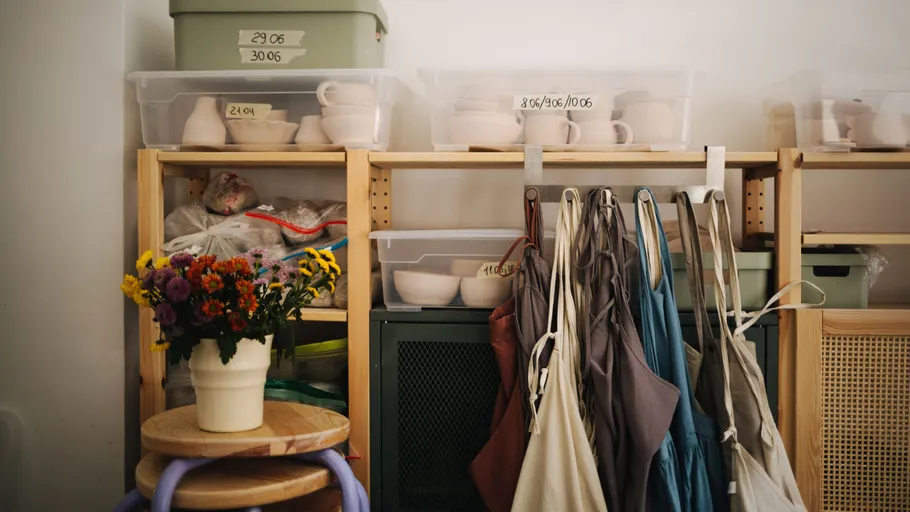Storage shelves with labeled bins, aprons, and flowers.