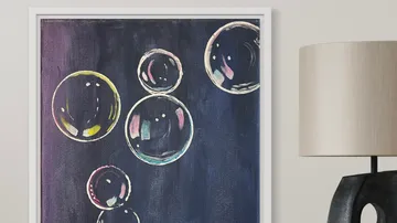 Soap bubbles float against a dark background, framed and illuminated.
