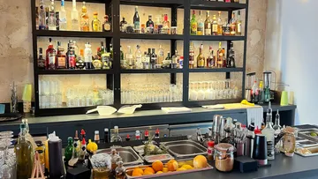 Bar mit vielen Spirituosen, Gläsern und Mixwerkzeugen.