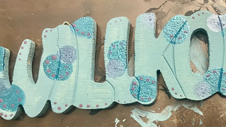 Colourfully painted wooden sign with the word “Welcome”