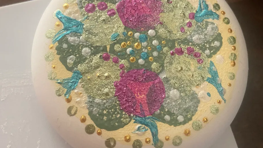 Buntes Mandala-Malerei auf rundem Felsen.