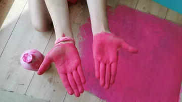 Hold red hands while pink paint is on the ground.