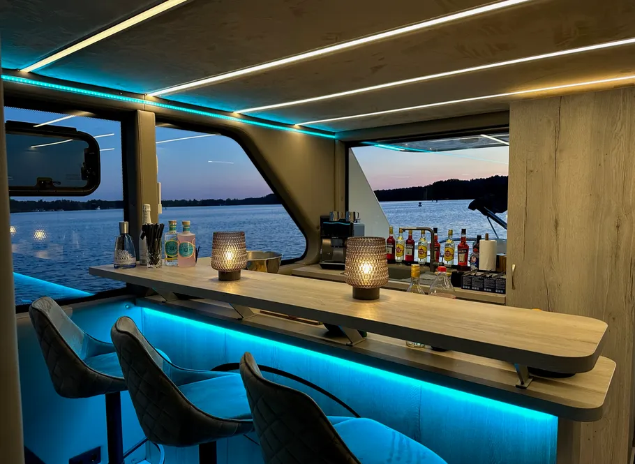 Modern yacht bar with blue lighting, overlooking water.