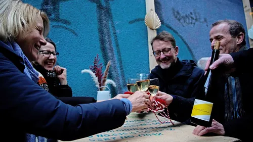 Vier Personen stoßen mit Gläsern auf einem Tisch an.
