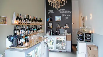 Wine rack with bottles; bistro atmosphere in a small shop.