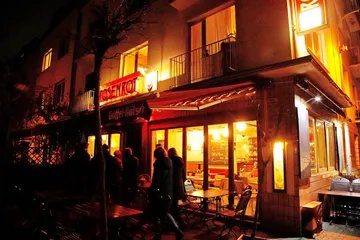 Restaurant with warm light, guests go in during the night.