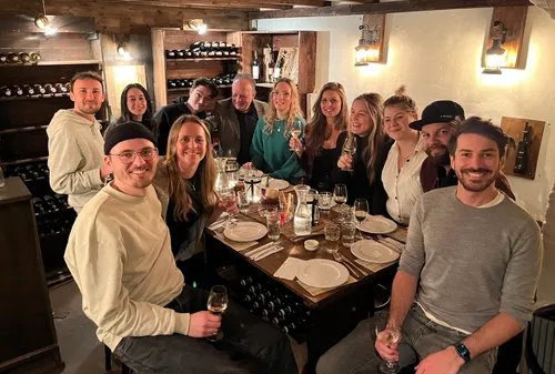 Group of people celebrating at table in wine cellar.