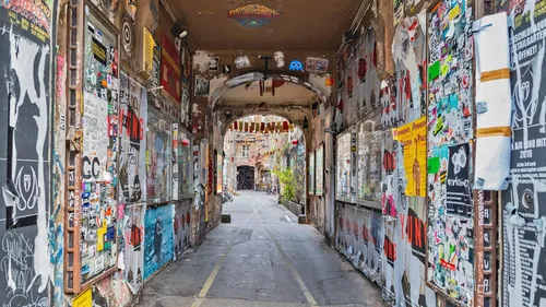 A passageway with posters and graffiti, colorfully decorated.