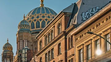 Kuppelgebäude reflektiert Sonnenlicht, umgeben von historischen Ziegelhäusern.