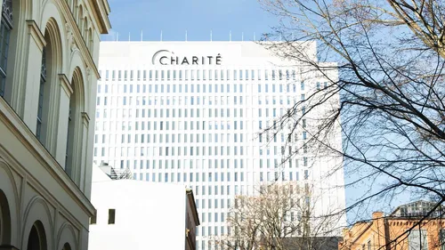 Skyscraper with “Charité” logo, surrounded by trees and buildings.