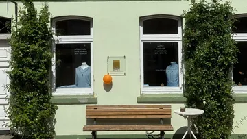 Blick auf Boutique mit Schaufenstern und Sitzgelegenheit draußen.