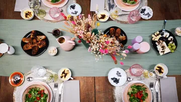 Essenstisch mit buntem Frühstück und dekorativen Blumenarrangements.