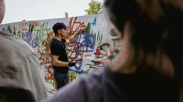 Sprayer zeigt Graffiti-Übungsaufgaben