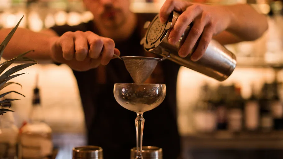 Barkeeper seiht Cocktails in ein Glas in einer Bar.
