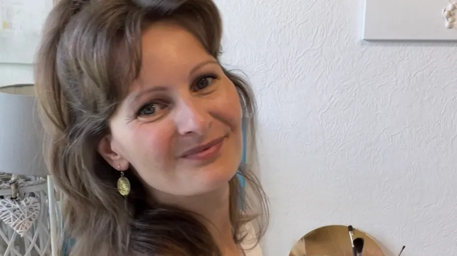 Frau lächelt, während sie in einem hellen Raum steht.