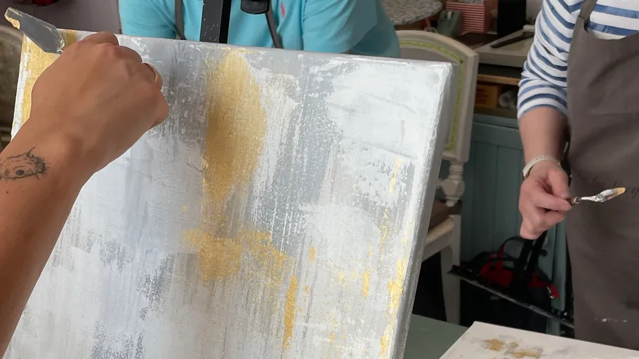 Ein Künstler malt eine Leinwand mit goldener Farbe.